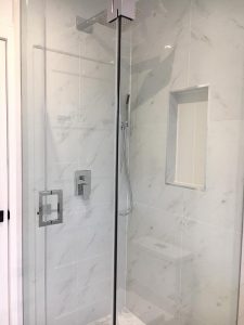 f Milman's Toronto bathroom renovation project, featuring the allure of white bathroom tiles, a refined walk in shower with glass enclosure