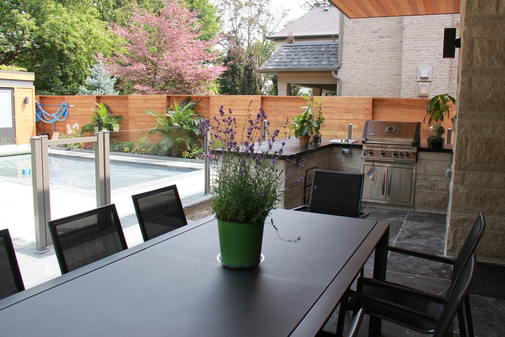 Home renovation project by Milman Design Build, Toronto Home Renovation contractors featuring Outdoor living area with custom outdoor kitchen, interlocking and glass railing over patio