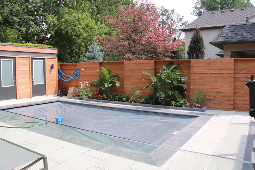 Home renovation project by Milman Design Build, Toronto Home Renovation contractors featuring Outdoor living area with custom outdoor kitchen, wooden fence, interlocking and custom pool