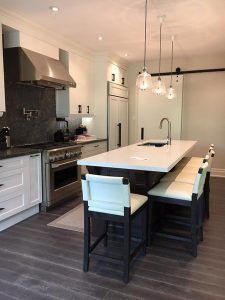 Milman Design Build renovated an Aurora home, creating a kitchen with a sink on the dining island, a cooktop, and kitchen cabinets, among other features.
