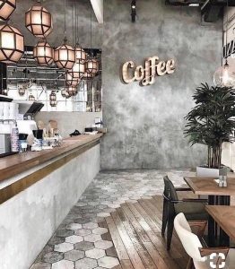 This image shows a restaurant renovated by Milman Design Build, with tables, chairs, chandeliers, and a coffee-themed painting on the wall.
