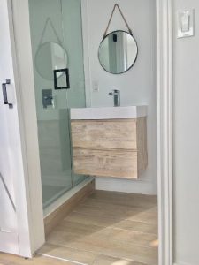 Sophisticated bathroom in Milman Design Build's Triplex Conversion, featuring wooden floors and pristine white walls.